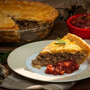 A slice of tourtiere on a plate with garnish.